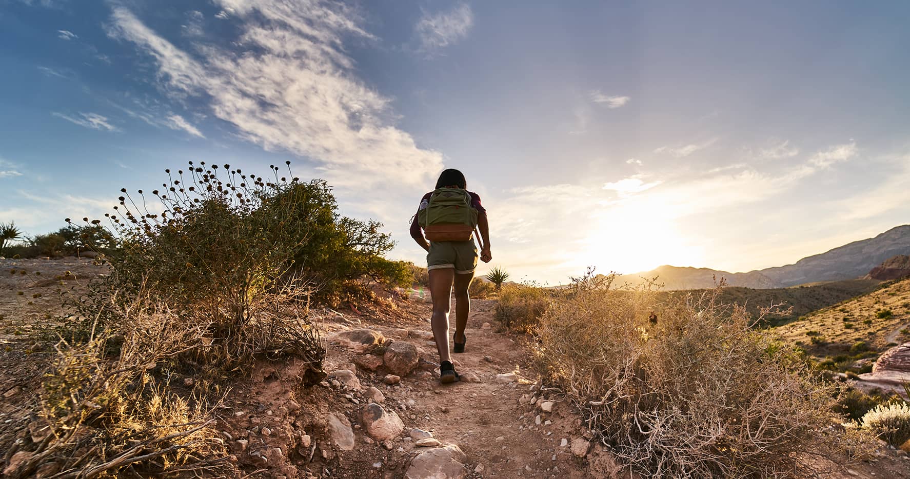 woman hiking through red rock canyon in nevada at sunset